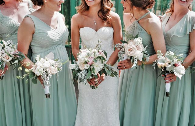 a bride in white surrounded by 4 bridesmaids in light green dresses